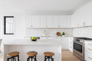 a beautiful kitchen detail with white cabinets, a gold faucet, white marble countertops, and a brown