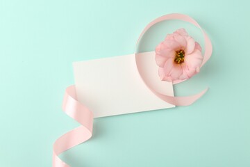 Wall Mural - Blank card, flower and ribbon on turquoise background, top view