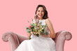 © Pixel-Shot - Beautiful bride with wedding bouquet in armchair on pink background