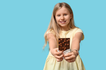 Canvas Print - Happy little girl with sweet chocolate bar on blue background