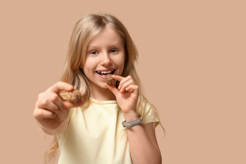 Wall Mural - Cute little girl with sweet chocolate candies on brown background