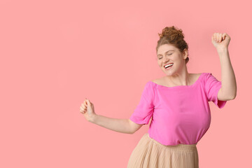 Wall Mural - Happy beautiful young woman dancing on pink background