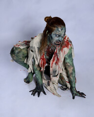 Canvas Print - portrait of scary female model wearing spooky halloween costume, ripped clothes and fake blood like an undead demon apocalyptic zombie character. Isolated figure, crawling poses dark studio background