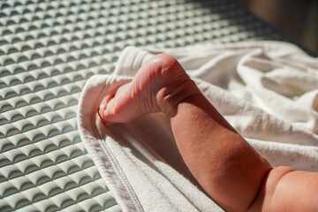 A close-up shot of a tiny baby's foot on a white blanket. The baby's skin is soft and delicate, Tiny Baby Foot on a White Soft Cozy Blanket Background.