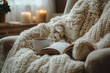 © kardaska - Open book resting on knit blanket with cup of tea near window