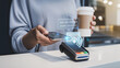 © ontsunan - Payment transaction with smartphone and coffee cup on a counter.
