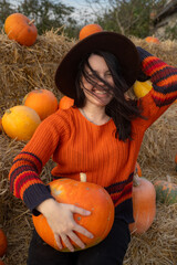 Wall Mural - Woman holding a pumpkin sitting on hay bales