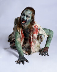 Canvas Print - portrait of scary female model wearing spooky halloween costume, ripped clothes and fake blood like an undead demon apocalyptic zombie character. Isolated figure, crawling poses dark studio background