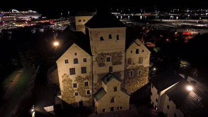 Wall Mural - Aerial orbit shot around the illuminated Turku castle, nighttime in Abo, Finland