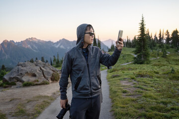 Man taking selfie photos in Paradise at sunset. Mount Rainier National Park. Washington State.