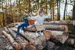 © Halfpoint - Portrait of family sitting on logs in the middle autumn forest, little girl jumping down, having fun.