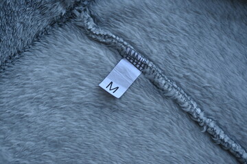 paper label size M on a gray background of plush fabric  