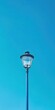 © Fokasu Art - A blue lamp shining in a blue sky, casting soft, serene light all around. Copy space for text.