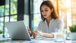 © chutikan - A businesswoman reviewing global marketing data on a laptop, preparing for a presentation, bright and modern office