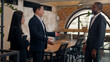 © Yuliia - Three business multiracial people coworkers partners colleagues in office two men businessmen African Asian Korea males handshaking hire talking Japanese Chinese Asian woman businesswoman assistant