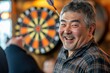 © ChaoticMind - A man smiles warmly in front of a dartboard, with casual attire, in a relaxed atmosphere, symbolizing happiness, leisure, and enjoying a game night.