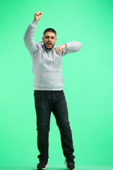 Canvas Print - A man, full-length, on a green background, rejoices