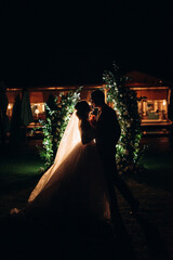 girl and guy against the background of a night wedding arch