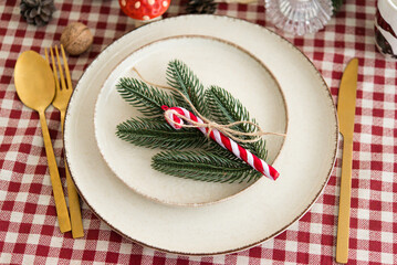 Wall Mural - beautiful christmas table setting, decor with green fir tree branch and candy cane on plates, cutler