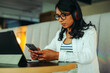 © Jacob Lund - Focused student texting on smartphone while studying at a cozy cafe with headphones and a laptop