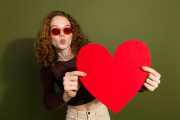 Sticker - Photo of cheerful pretty teen lady dressed brown clothes rising big red heart sending you kiss empty space isolated green color background