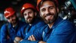 © familymedia - Group of smiling construction workers wearing blue coveralls and helmets, demonstrating camaraderie and teamwork in a positive work environment.