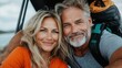 © familymedia - A happy couple smiles directly at the camera with a forested or mountainous outdoor setting, featuring backpacks indicating they are on a hiking or adventure trip.
