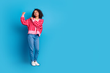 Wall Mural - Portrait photo of american beautiful girl with curly hair wearing shirt and jeans at party dancing isolated on blue color background