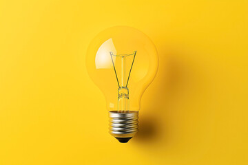 Close-up of a light bulb on a bright yellow background, highlighting the bulb's metal base and glass enclosure. The image emphasizes electrical innovation and creativity.