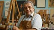 © Vadym - Serene studio scene with mature man in brown apron. Seated at wooden easel, holding paintbrush, palette. Focused gaze, engaged in work. Art supplies fill studio, including paint tubes, brushes,