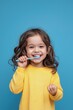 © Andrii Zastrozhnov - A young girl is brushing her teeth with a blue toothbrush. She is smiling and she is enjoying the activity