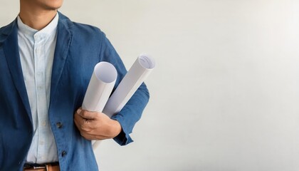 Man holding architectural plans standing in a minimal setting.