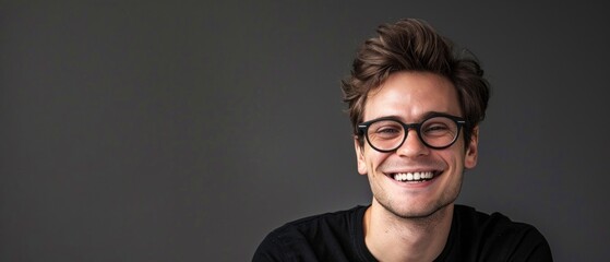 Wall Mural - Close-up photo of a smiling white man with curly hair, wearing black T-shirt and round glasses. Positive, light-hearted atmosphere with cheerful expression.