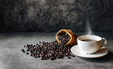 Americano coffee cup and roasted coffee beans falling in a burlap sackon gray background, Black coffee cup aromatic