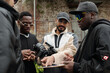 © pressmaster - Group of young creatives examining film equipment and discussing project outdoors. Focused members are interacting, capturing ideas, and collaborating in urban setting