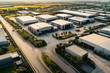 © OMD - Aerial view of a large industrial park featuring multiple warehouse buildings and clear roads, surrounded by greenery and open spaces.