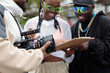 © pressmaster - Filming crew holding camera and reviewing script on clipboard during an outdoor film shoot. Team members focused on scene planning without direct eye contact with camera