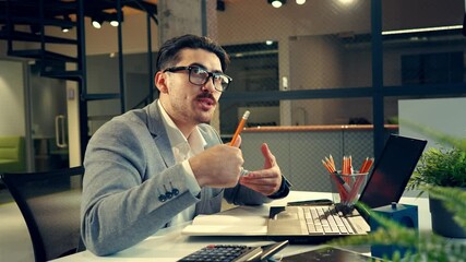 Poster - Professional man in office attire engaged in a focused discussion while using a laptop and taking notes at his desk during working hours