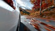 © svastix - A dynamic side view of a silver car speeding along a mountain road, flanked by autumn leaves and majestic snow-capped peaks in the background.