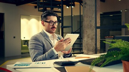 Poster - professional man reviewing documents on a tablet in a modern office space during the day