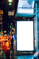 Wall Mural - Bus station billboard in rainy night with blank copy space screen for advertising or promotional content, empty mock up Lightbox for information, blank display in urban city street with long exposure