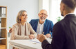 © Studio Romantic - Senior couple client consults with a real estate agent and financial consultant or adviser, sitting at a table in an office. They discuss insurance, investments, and other aspects of meeting.