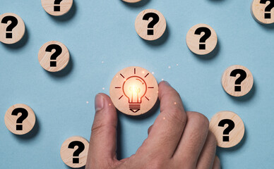 Poster - Hand holding glowing light bulb inside magnifier glass among question mark for focus and concentrate of creative thinking idea and problem solving concept.
