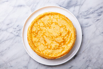 Wall Mural - Crepes, thin pancakes on a white plate. Marble background. Copy space. Top view.