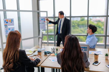 Asian businessman presenting business plans and strategies to team members in an office setting, emphasizing collaboration and corporate growth during a formal meeting aimed at teamwork success.