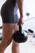 © 9nong - Healthy strong fit Asian fitness woman working out in indoors gym, single handed kettlebell hold for core, hamstrings, quads, glutes, back, deltoids, and arm muscles, hand closeup shot