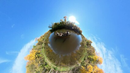 Wall Mural - Couple paddling canoe in tiny planet clip on autumn river. Blue sky
