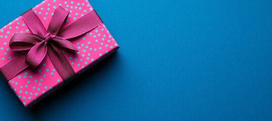 Canvas Print - This is a picture of a gift box with pink ribbon on a blue background, featuring polka dots in light indigo and pink.