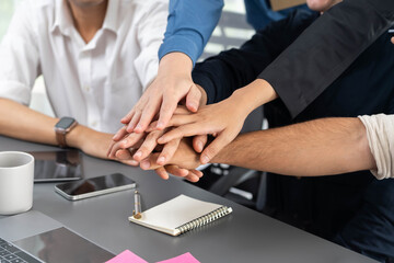 Group of diverse office worker join hand together in office room symbolize business synergy and strong productive teamwork in workplace. Cooperation and unity between business employee. Prudent