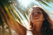 © Minerva Studio - Young woman enjoying sunlight under palm tree on tropical beach